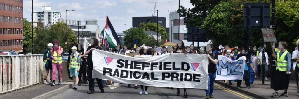 A photo of the front of the Sheffield Radical Pride March. A Palestinaian flag is visible.